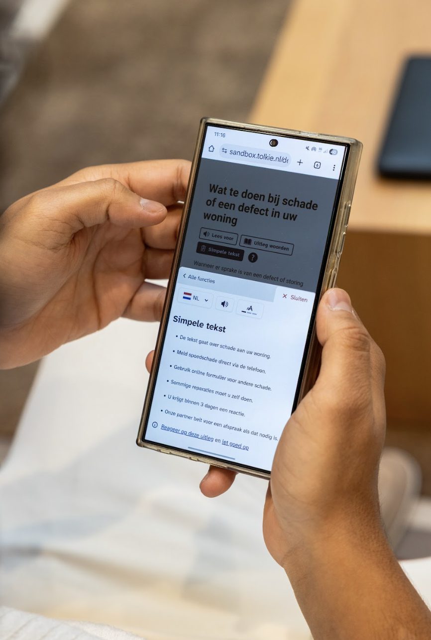 Iemand opent Tolkie Leeshulp op een telefoon en leest een simpele versie van een tekst over schade aan een woning