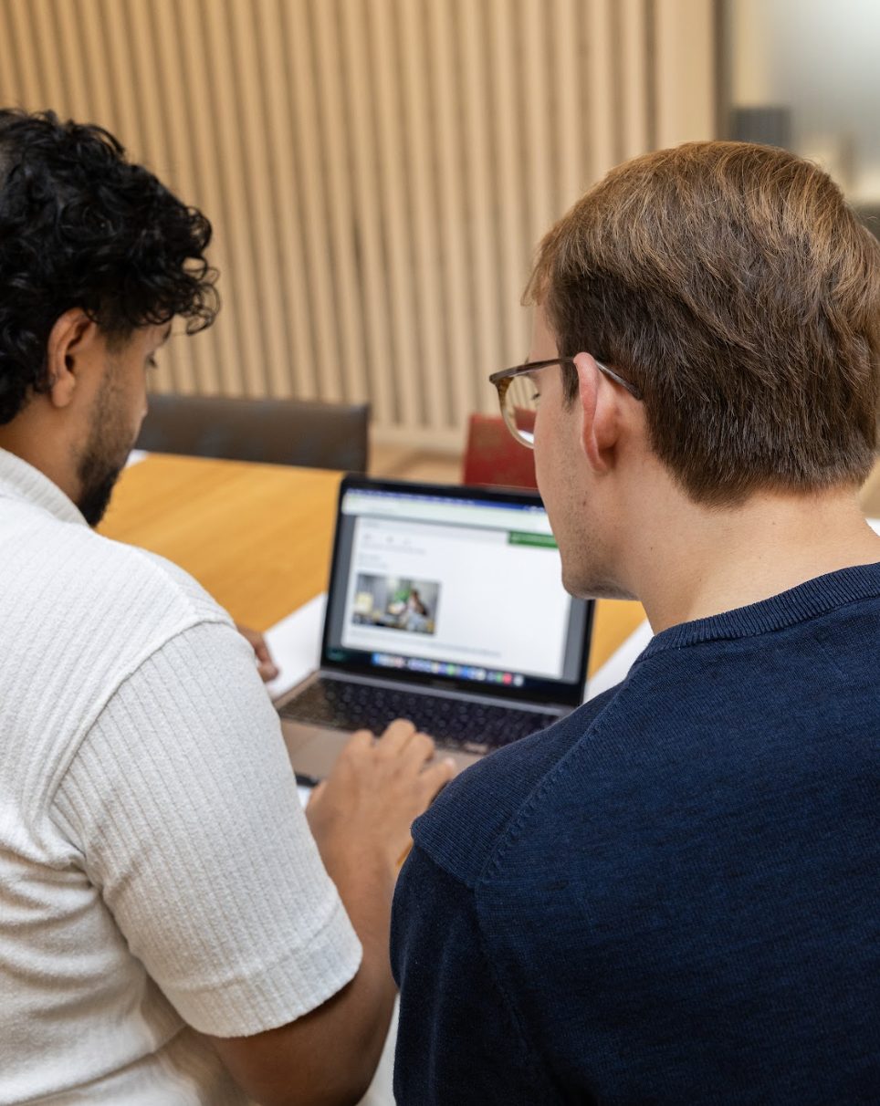 Twee collega's overleggen samen achter een laptop