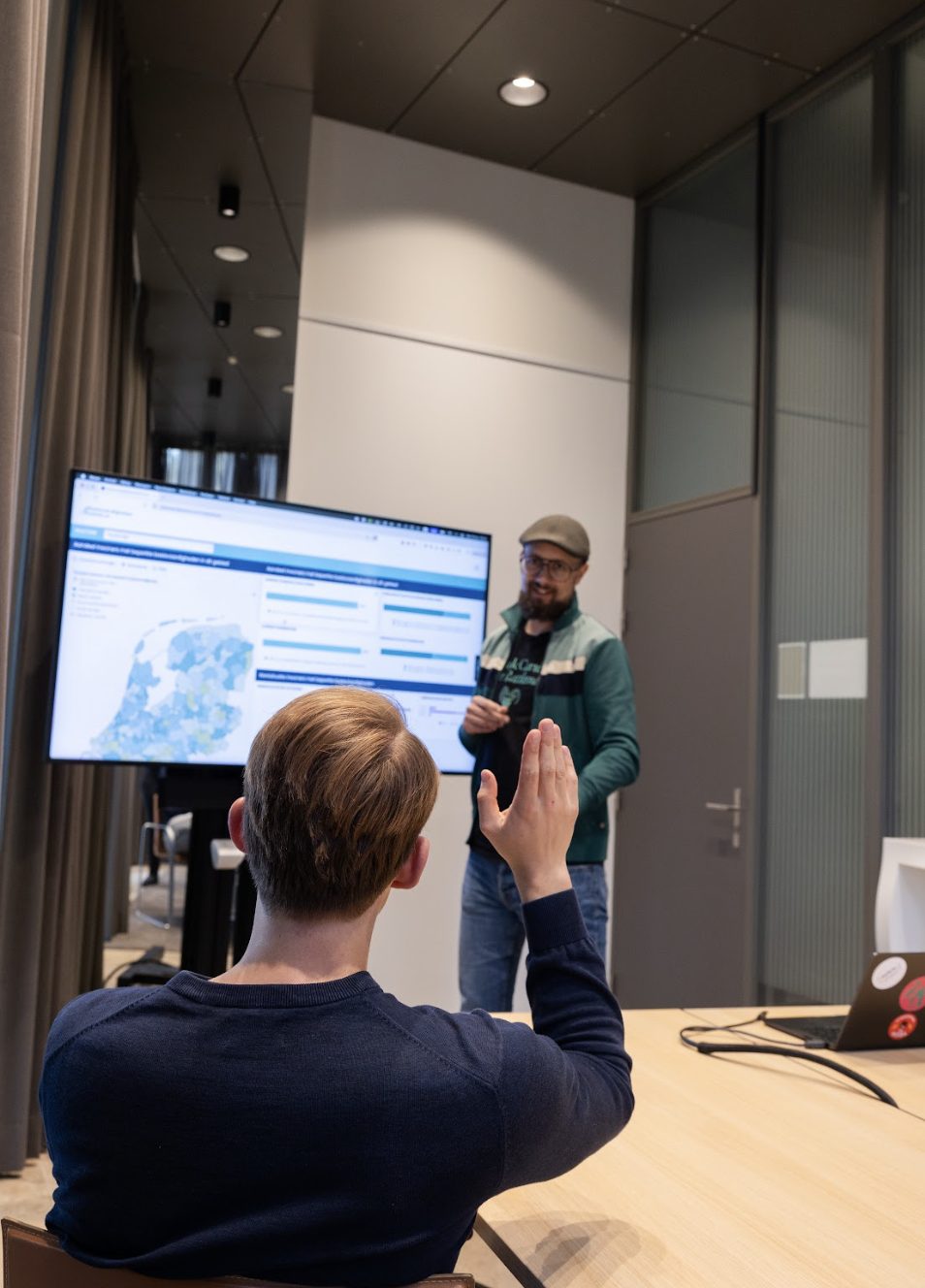 Twee collega's bespreken een digitale kaart op een groot scherm tijdens een workshop