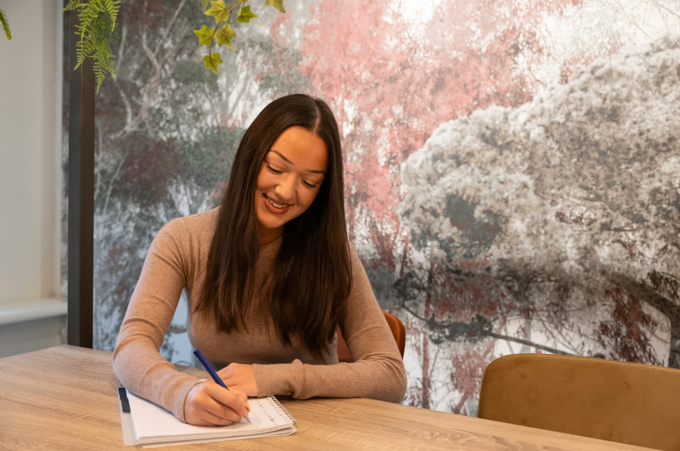 Vrouw die geconcentreerd aantekeningen maakt in een notitieblok tijdens een workshop